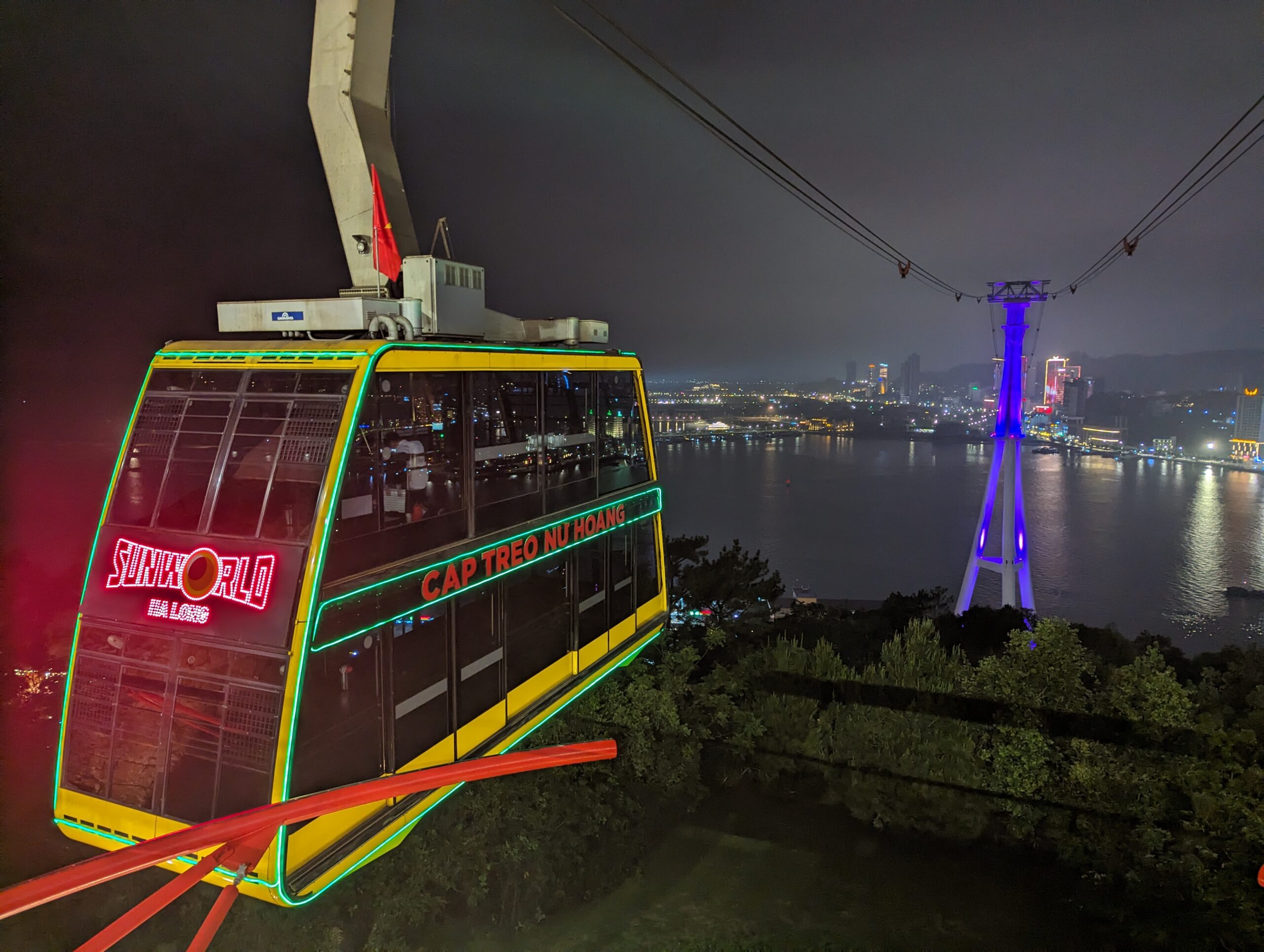 Seilprüfung-Vietnam HaLong - Seilprüfung in Vietnam – beleuchtete Gondel bei Nacht Seilprüfung in Vietnam – gelbe Gondel mit Neonbeleuchtung bei Nacht
