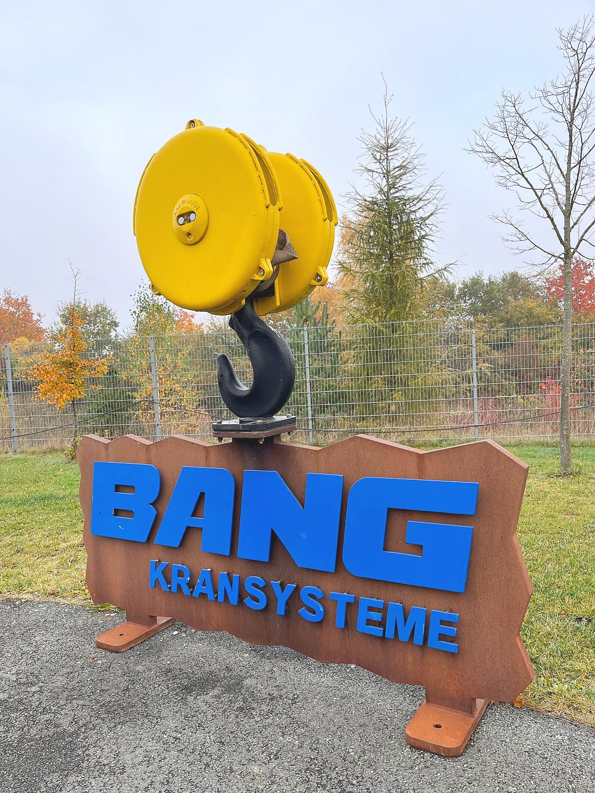 Krankanhänger mit großem BANG Kransysteme-Schild auf dem Firmengelände
