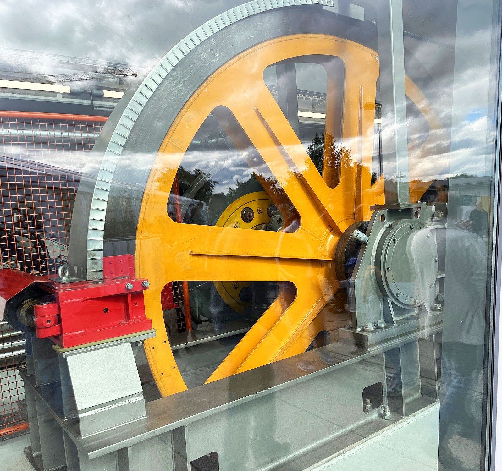 Gelbes Antriebsrad der Seilbahn in Künzelsau Seilbahnfest Künzelsau – großes gelbes Antriebsrad hinter Glasscheibe.