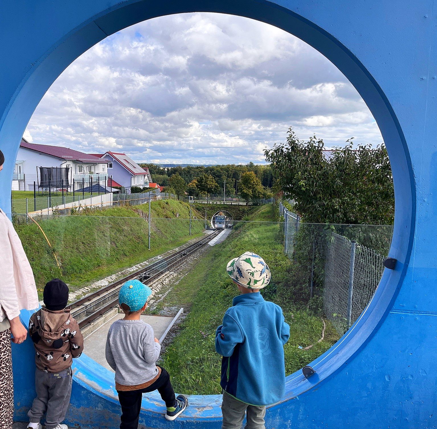 Kinder am Fenster mit Blick auf die Seilbahn Seilbahnfest Künzelsau – Kinder blicken durch rundes Fenster auf die Bergbahn.
