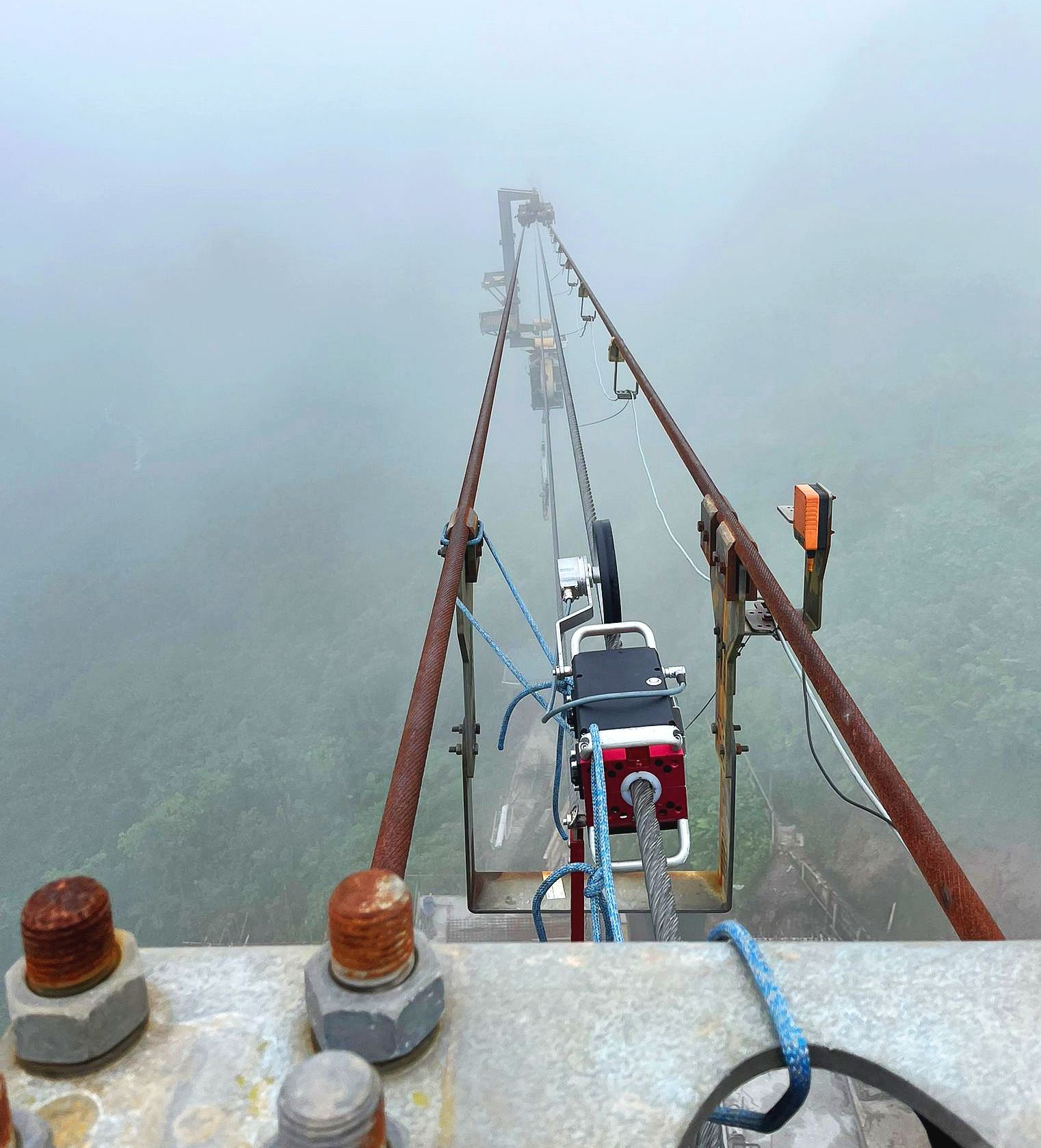 Prüfgerät von ROPESYS am Zugseil, das im Nebel den Berg hinabführt