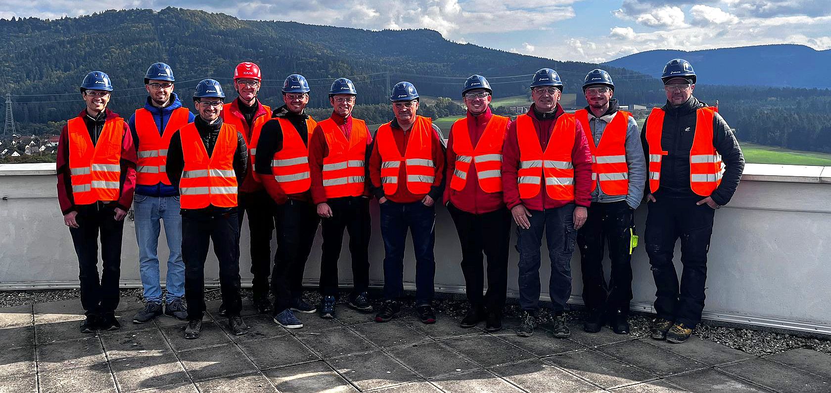 ROTEC-Team mit Helmen und Sicherheitswesten auf der Dachterrasse von Holcim mit Blick auf die Landschaft