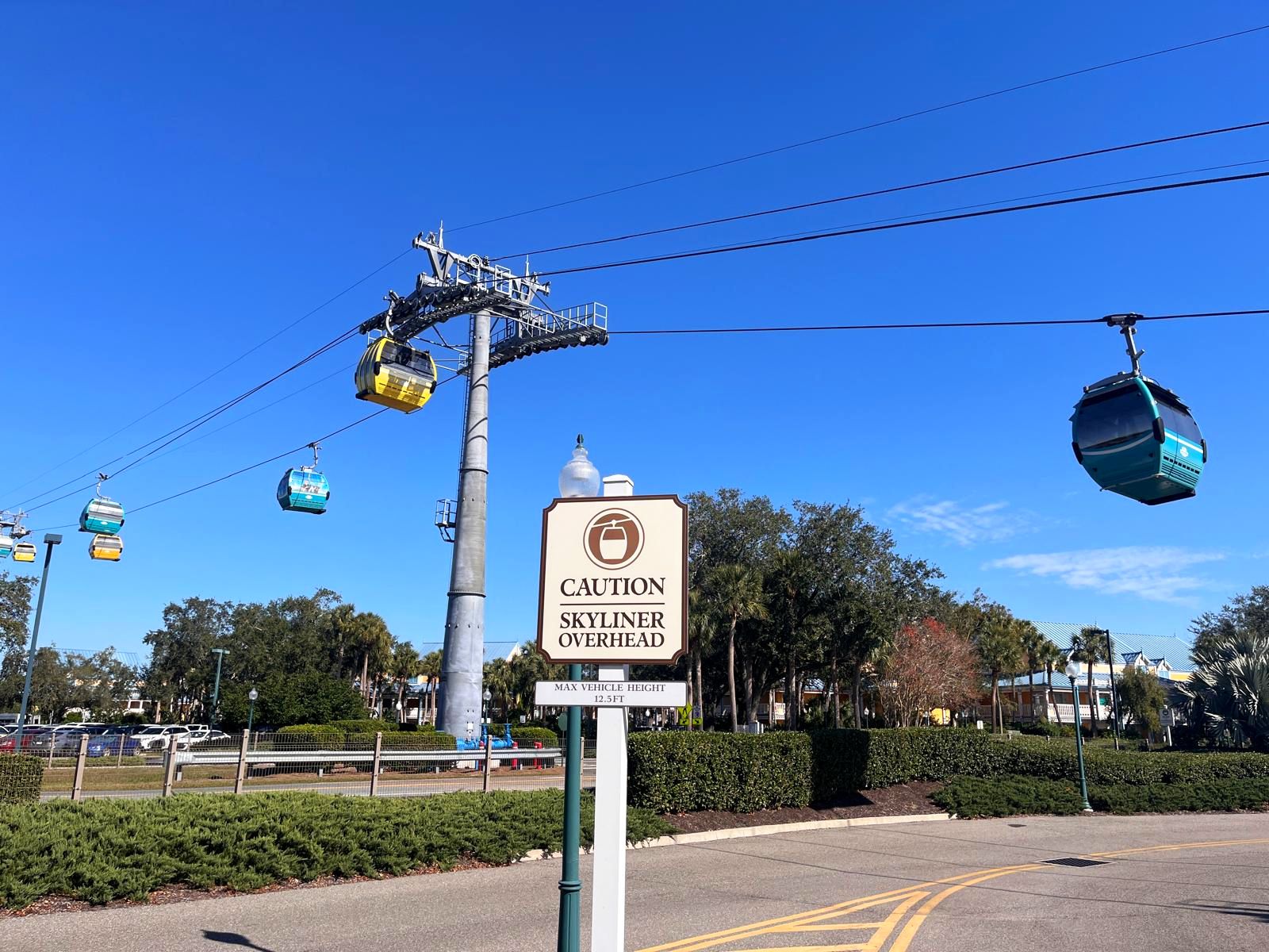 Disney Skyliner Gondeln über einer Straße mit Warnschild