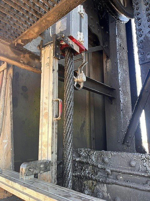 The ROPESYS rope testing device mounted on a vertical steel cable thickly coated with black grease.